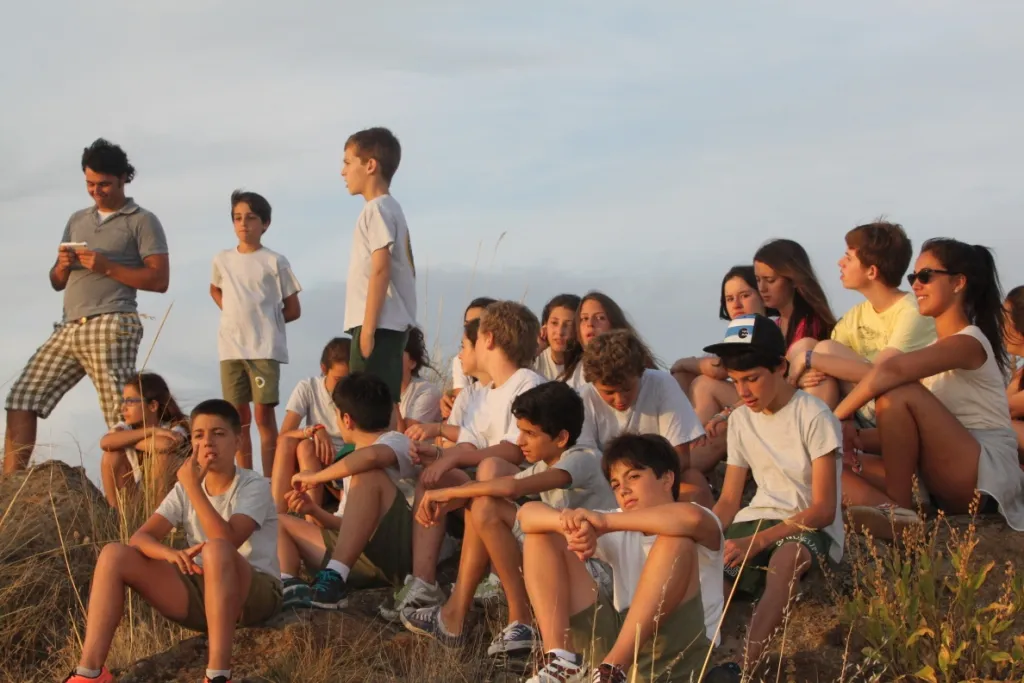 A group of campers sitting on a hillside at sunset