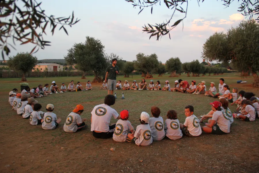 Un groupe assis en cercle sur la pelouse du camp de Layos